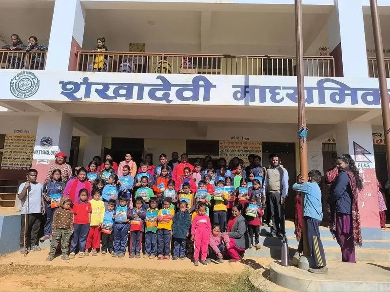 Students and teachers gathered outside Shankha Devi Secondary School holding learning materials